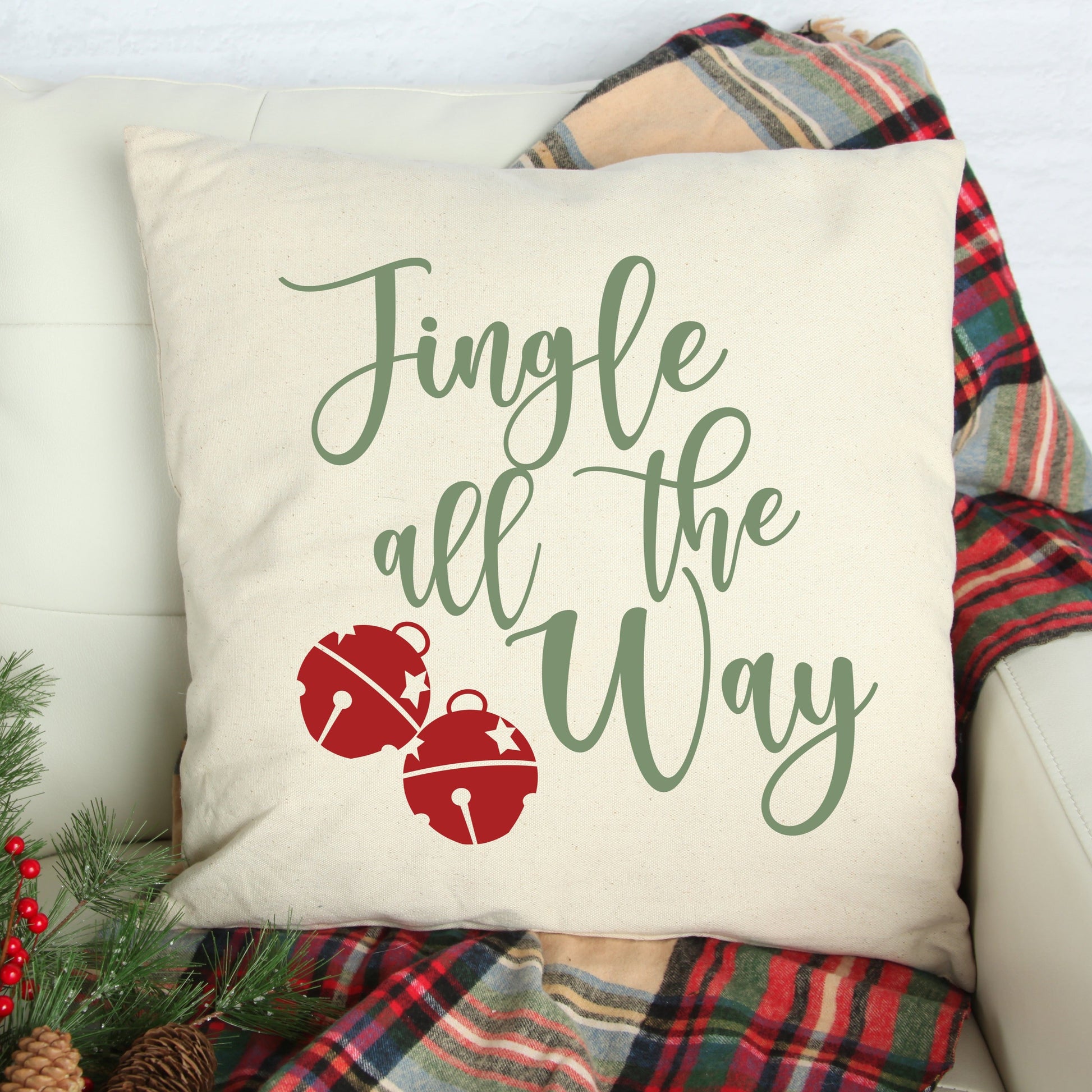 Jingle All the Way Pillow Cover 17x17 inch displayed on a cozy couch, featuring holiday-themed design and plaid blanket.