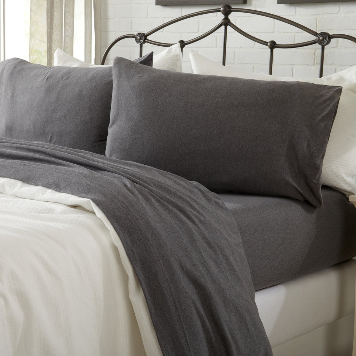 Gray bedding set on a bed with a white headboard.