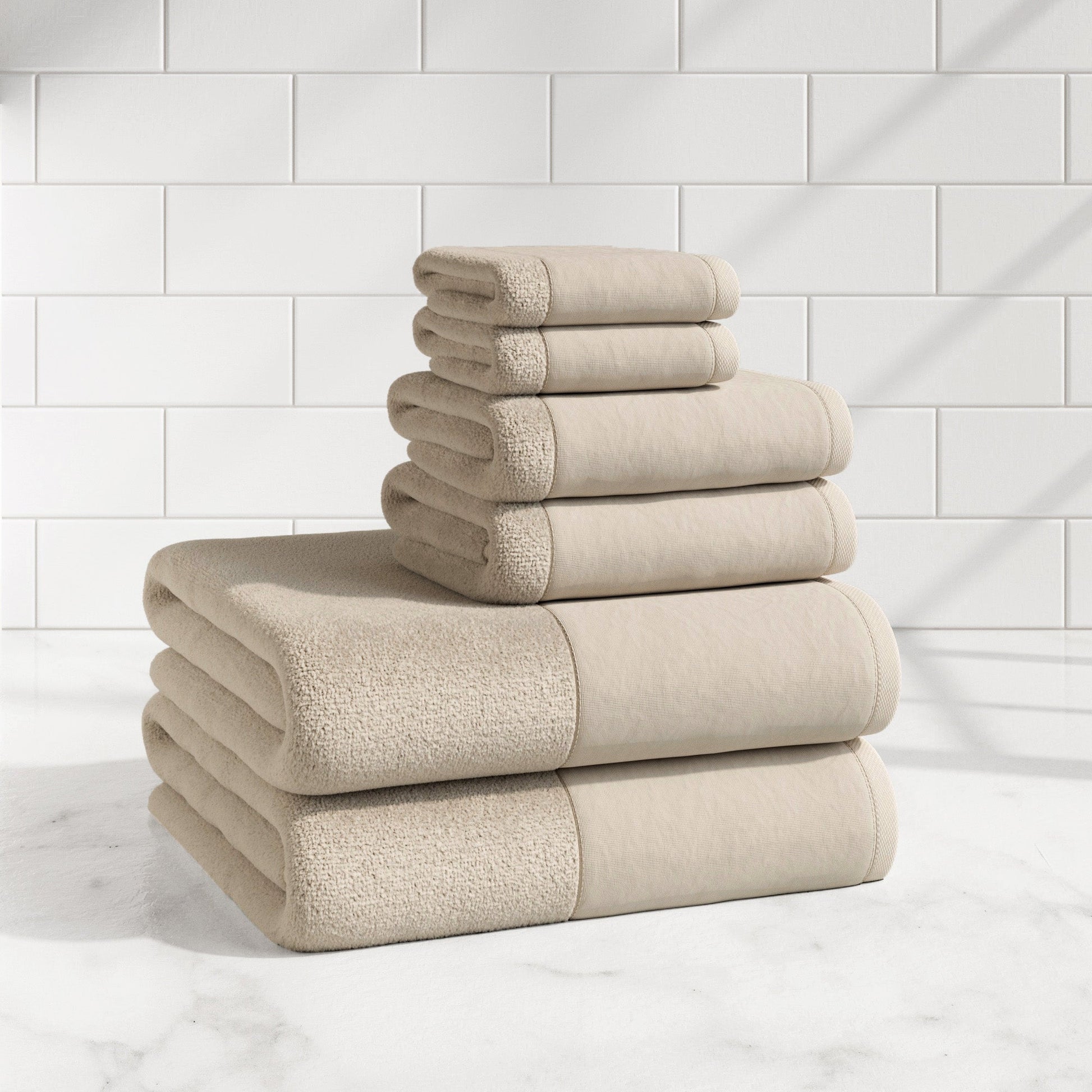 Stack of beige towels on a marble surface with a tiled wall background