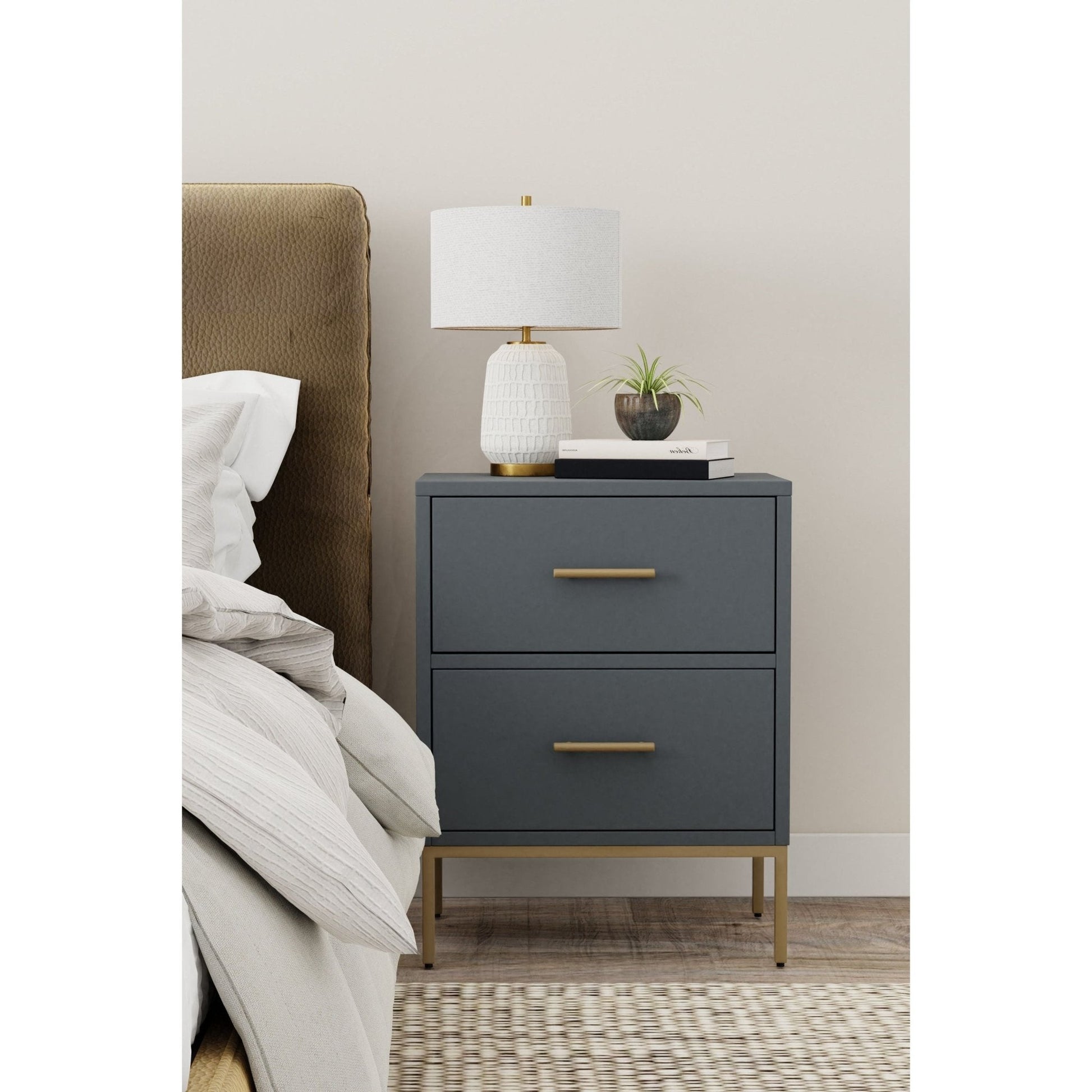 Madelyn Two Drawer Nightstand in Slate Gray with gold hardware, alongside a lamp and decor in a modern bedroom setting.