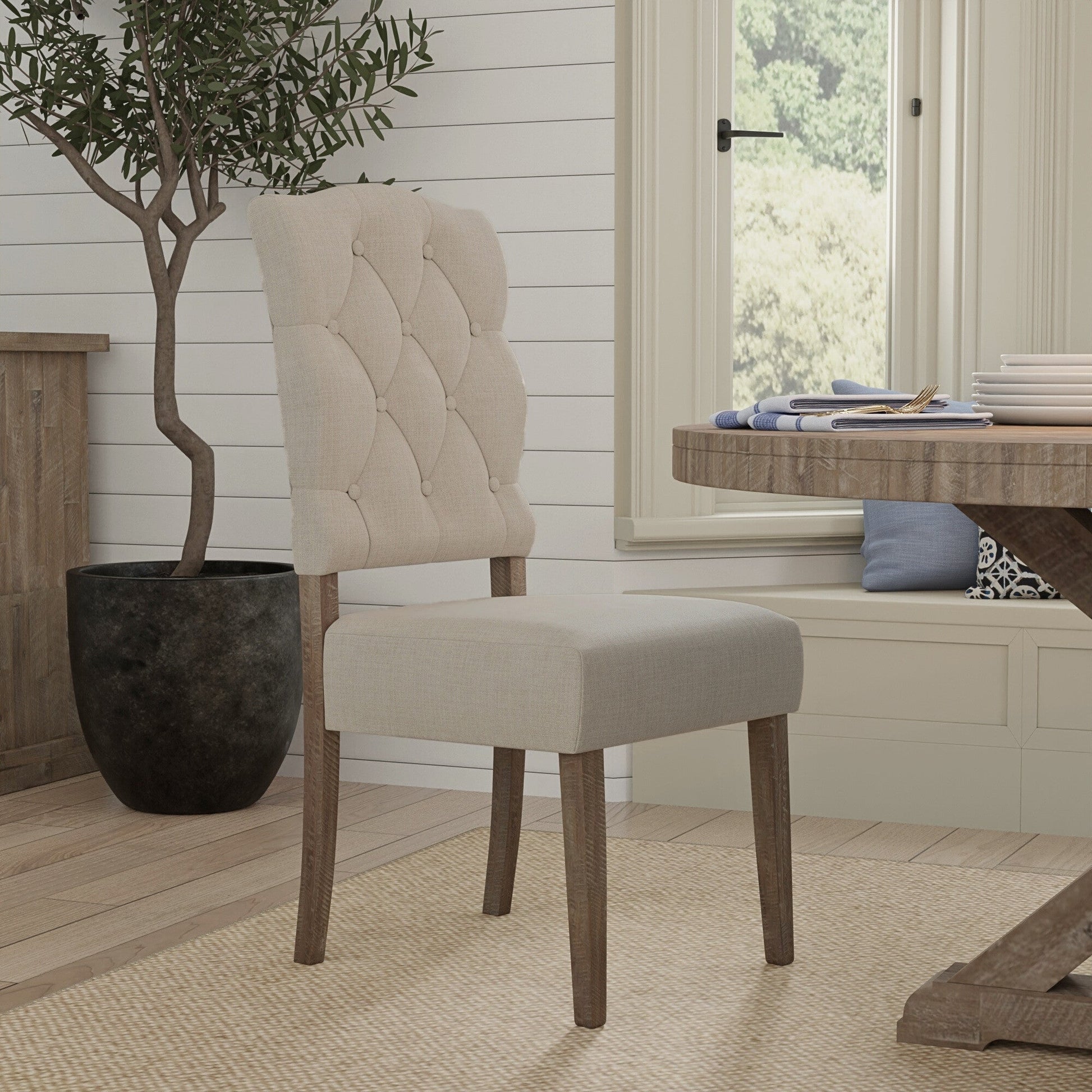 Newberry Side Chairs with weathered wood legs and button-tufted detail in a cozy dining room setting.