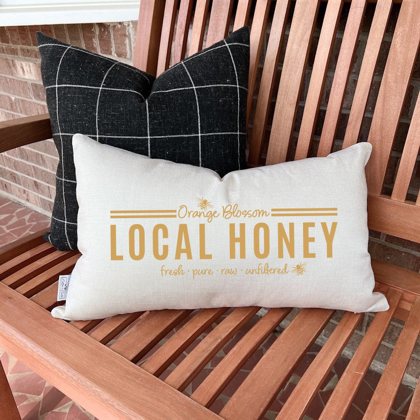 Orange Blossom Honey Summer Pillow Cover 12x20 inch on a bench with black checkered pillow behind it.
