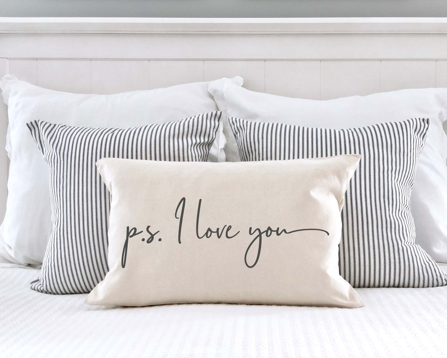 P.S. I Love You Valentine's Day Pillow Cover 12x20 Inch on a bed with striped pillows.