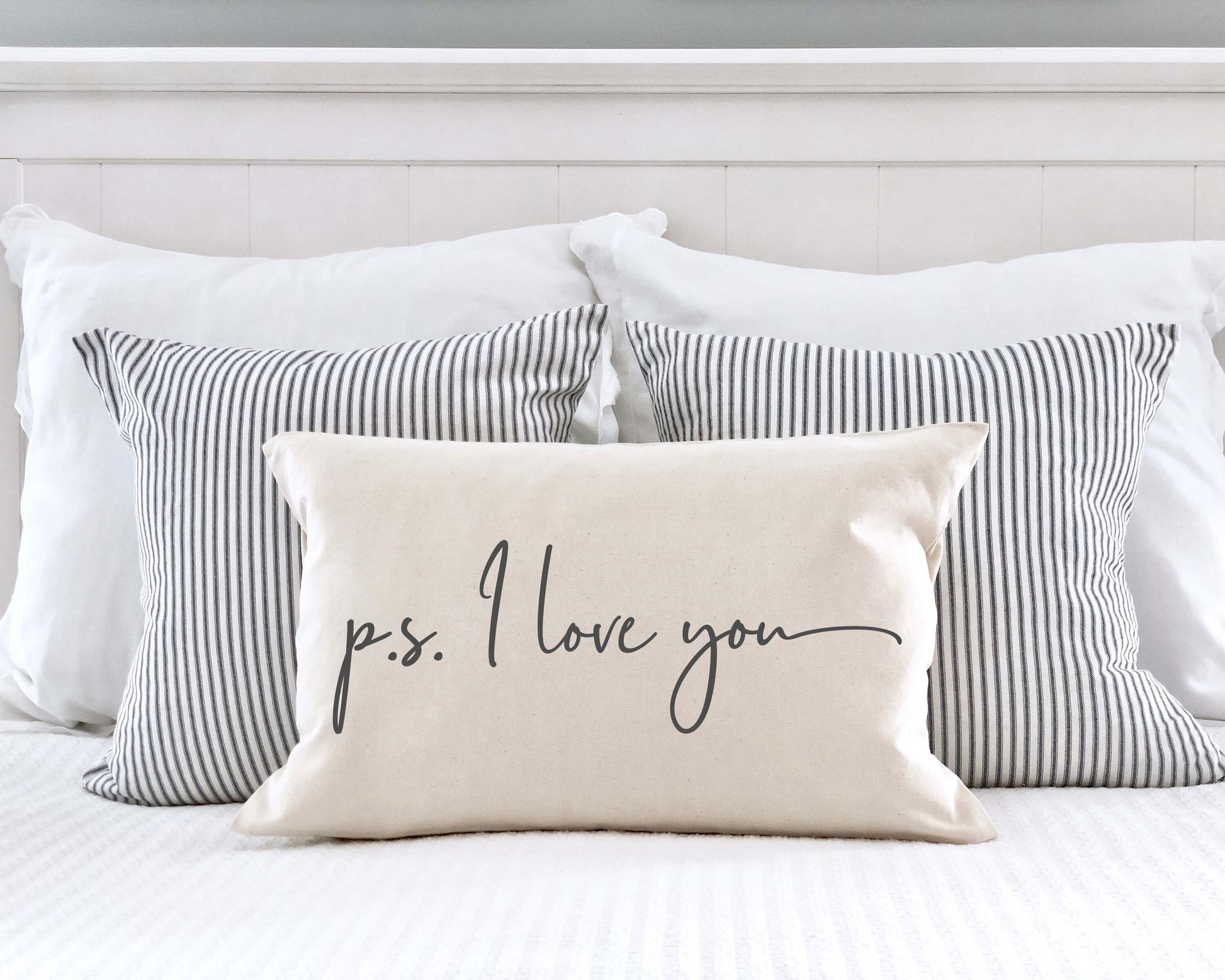 P.S. I Love You Valentine's Day Pillow Cover 12x20 Inch on a bed with striped pillows.