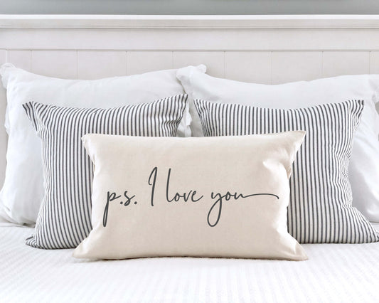 P.S. I Love You Valentine's Day Pillow Cover 12x20 Inch on a bed with striped pillows.