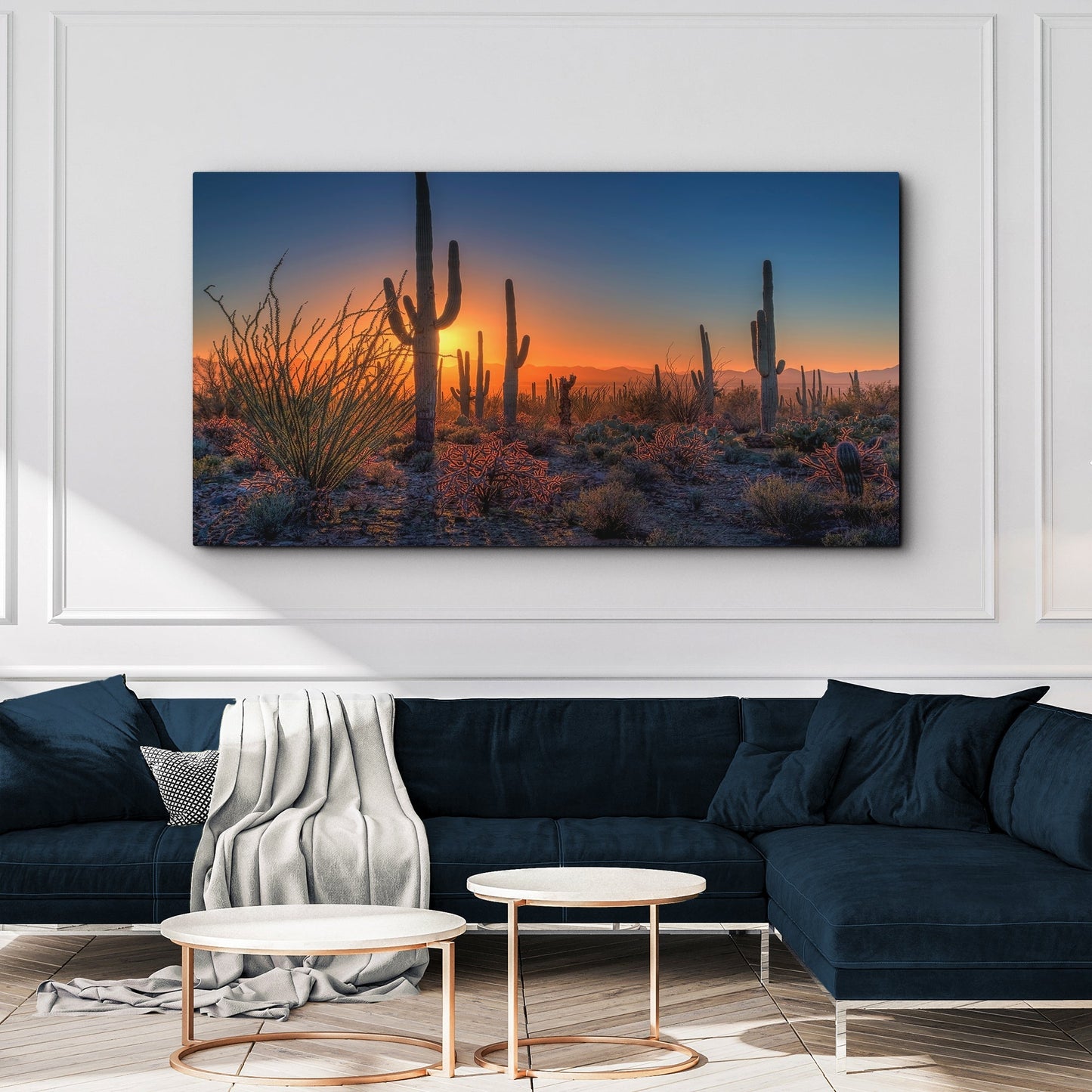 Desert landscape painting above a dark blue sofa in a living room.