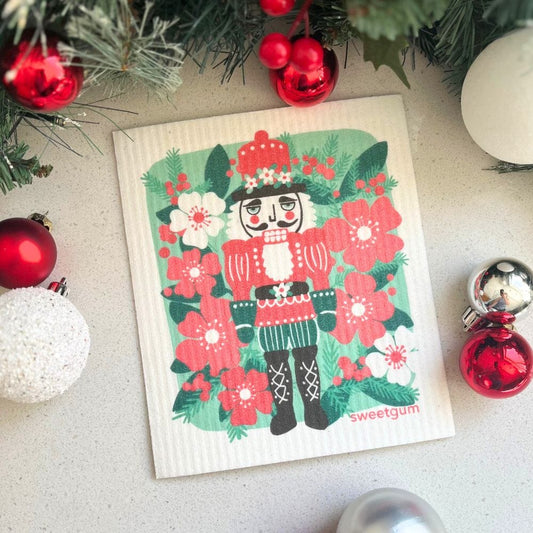 Christmas-themed dishcloth with nutcracker design surrounded by festive decorations