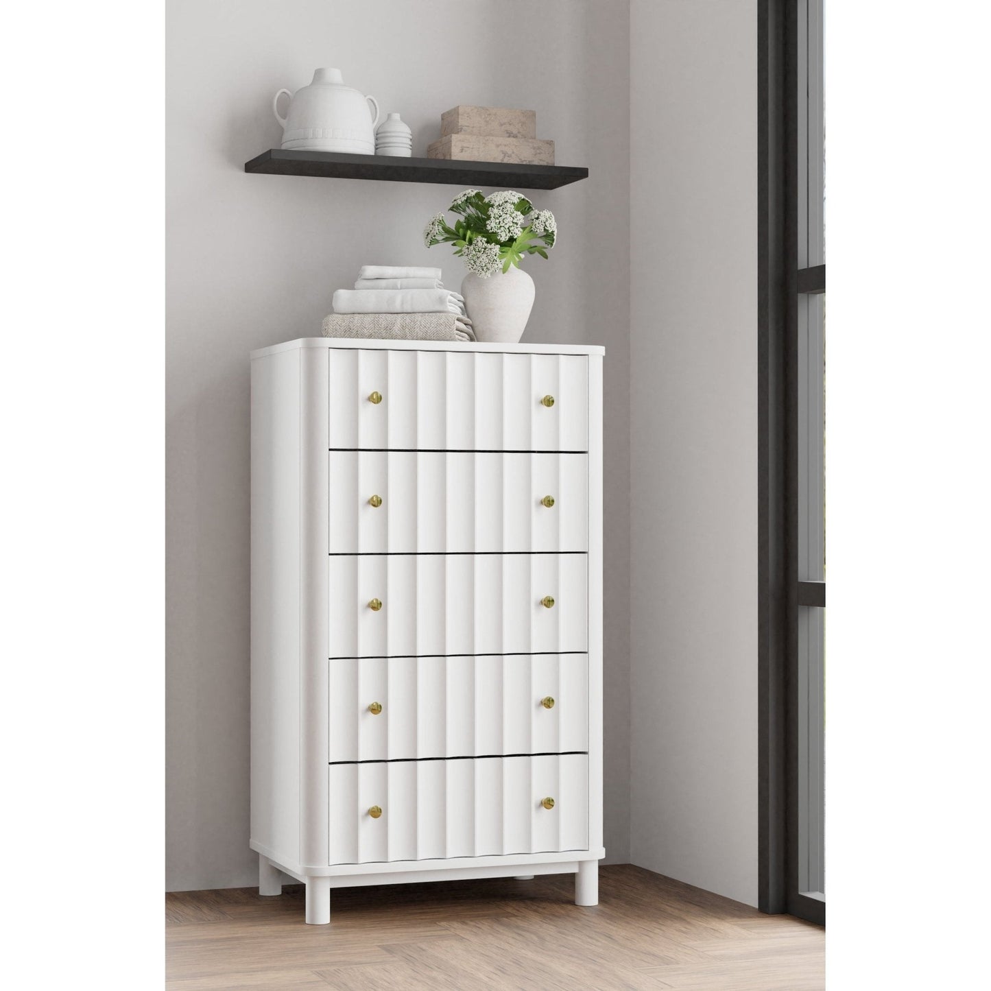 Stapleton Five Drawer Chest in white finish with gold knobs, displayed in a modern bedroom setting.
