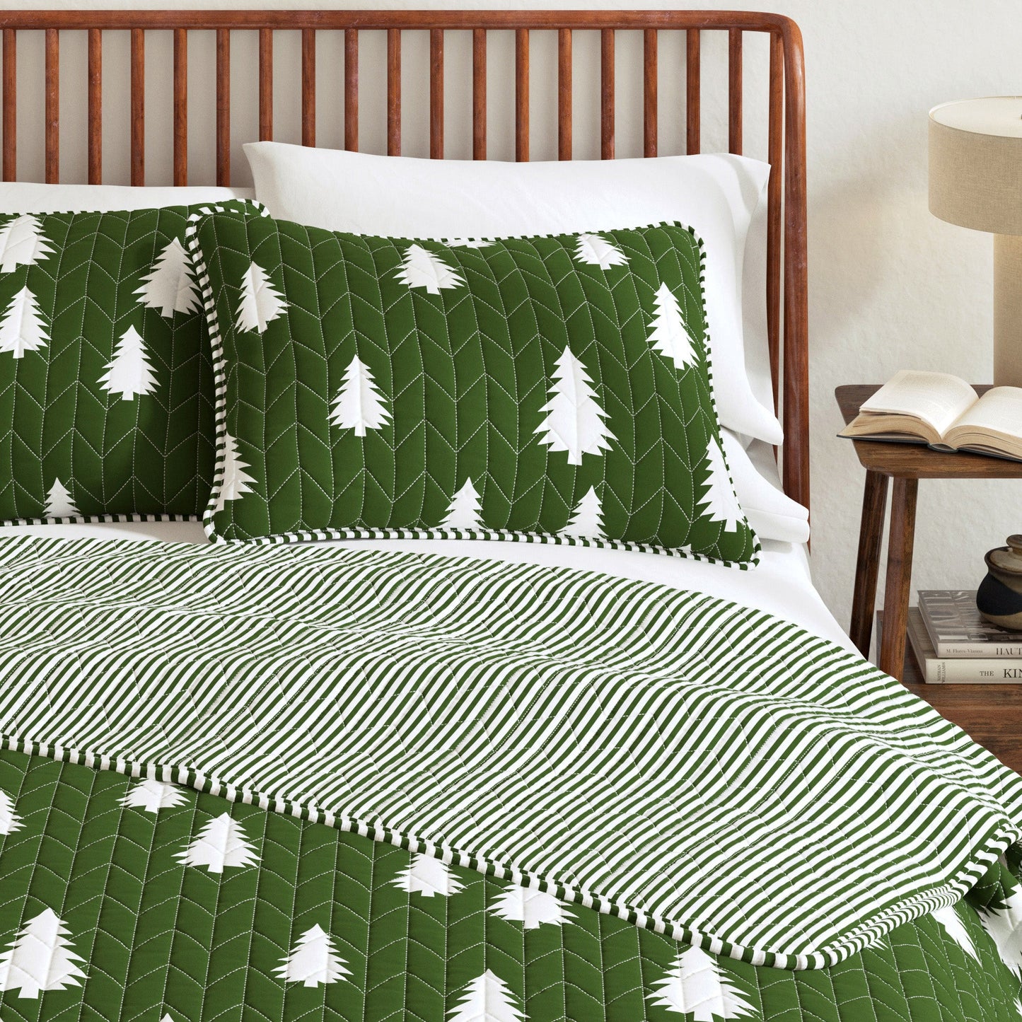 Bed with green and white tree-patterned bedding and quilt