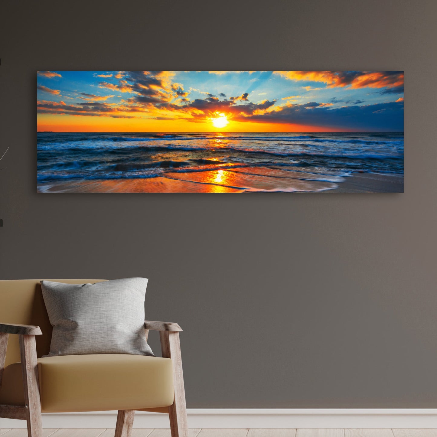 Panoramic sunset over the ocean on a wall above a chair with a pillow.