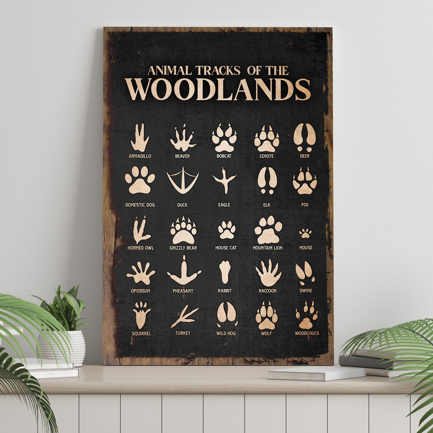 Print titled 'Animal Tracks of the Woodlands' with various animal tracks on a wooden frame.