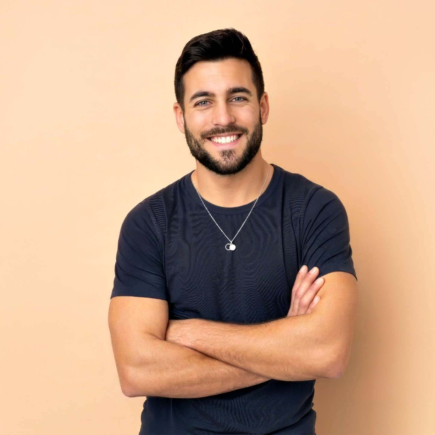 The Empty Tomb Pendant Necklace worn by a smiling man with arms crossed against a light background.