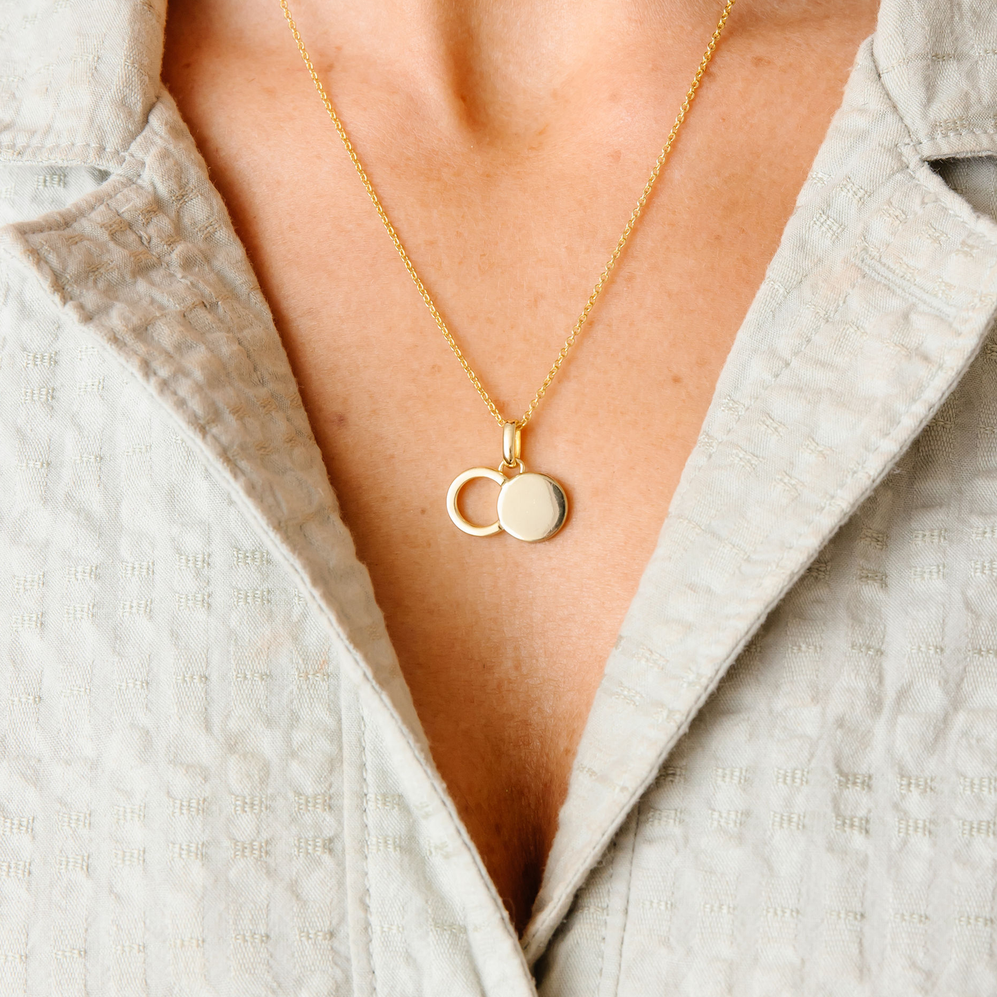 The Empty Tomb Pendant Necklace worn on a person's neckline, featuring a gold chain and circular pendant.