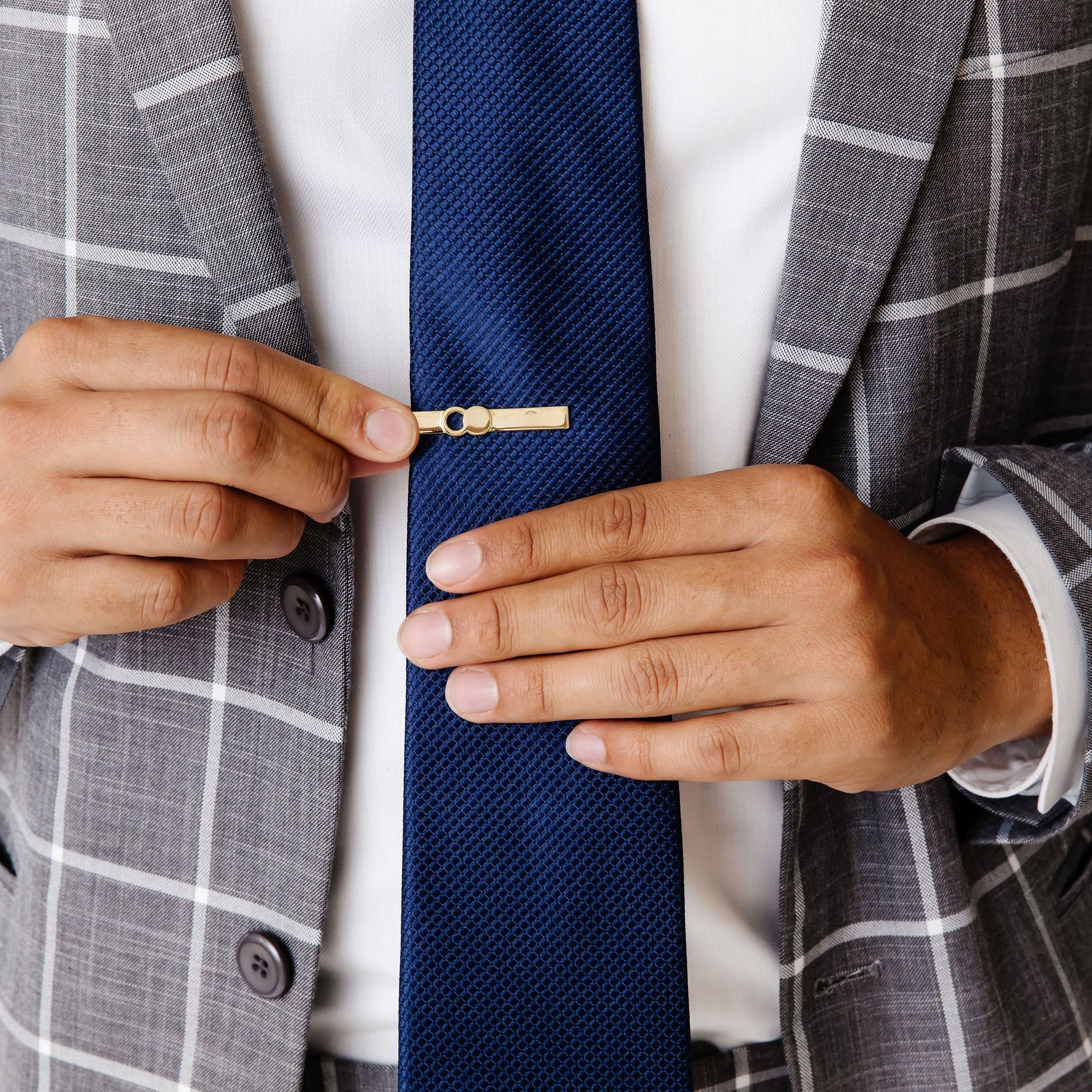 The Empty Tomb Tie Clip attached to a blue tie worn with a stylish gray suit.