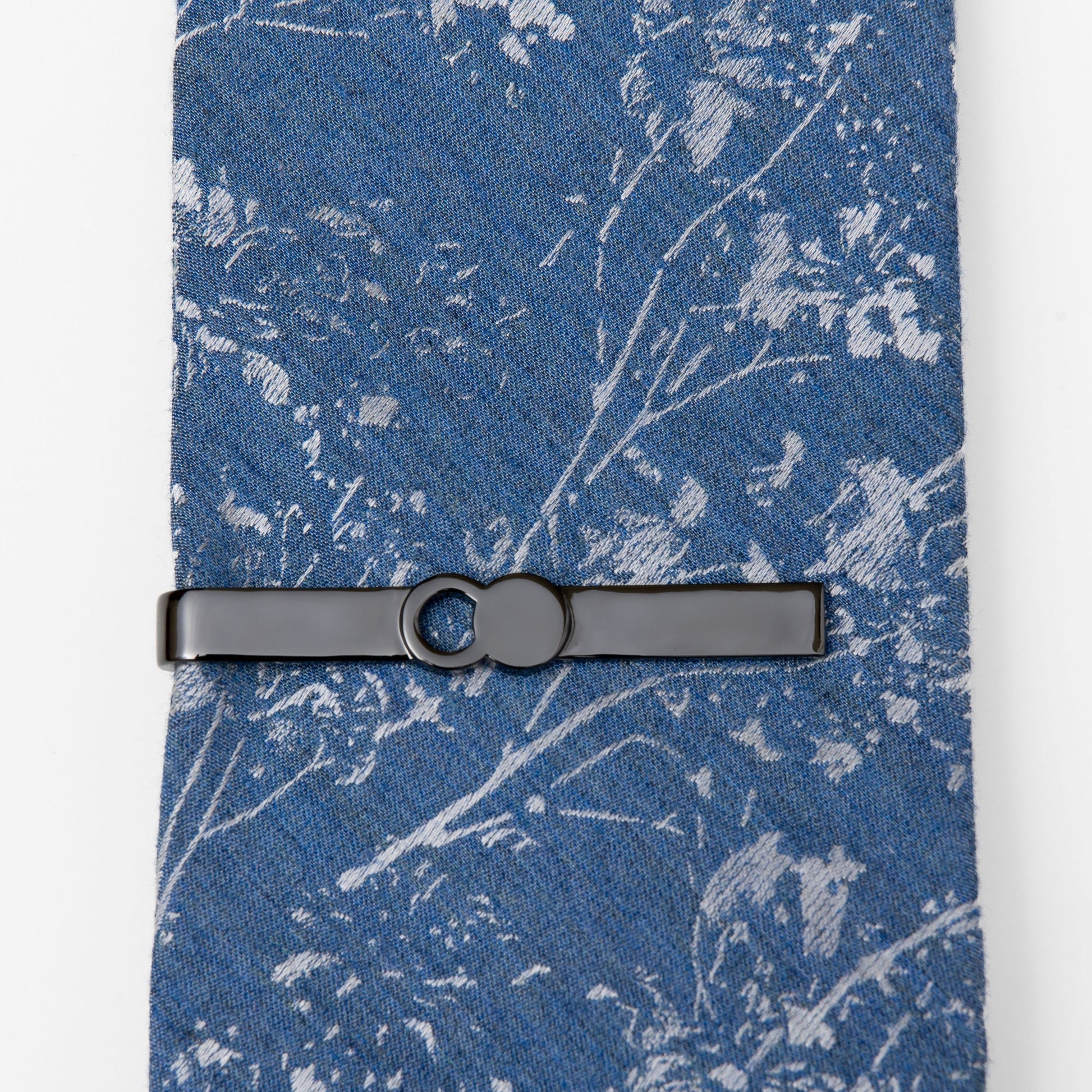 The Empty Tomb Tie Clip resting on a blue patterned tie, showcasing its sleek design and craftsmanship.