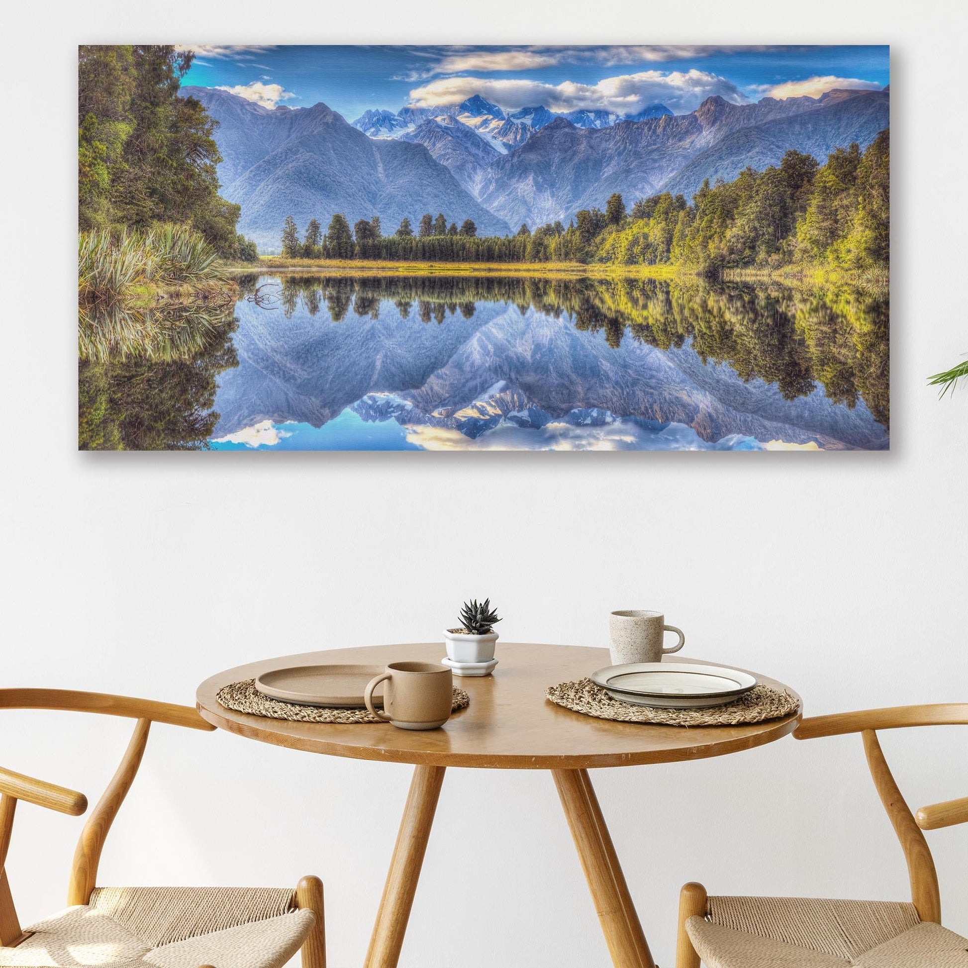 Dining room with a large mountain landscape painting on the wall above a wooden table.