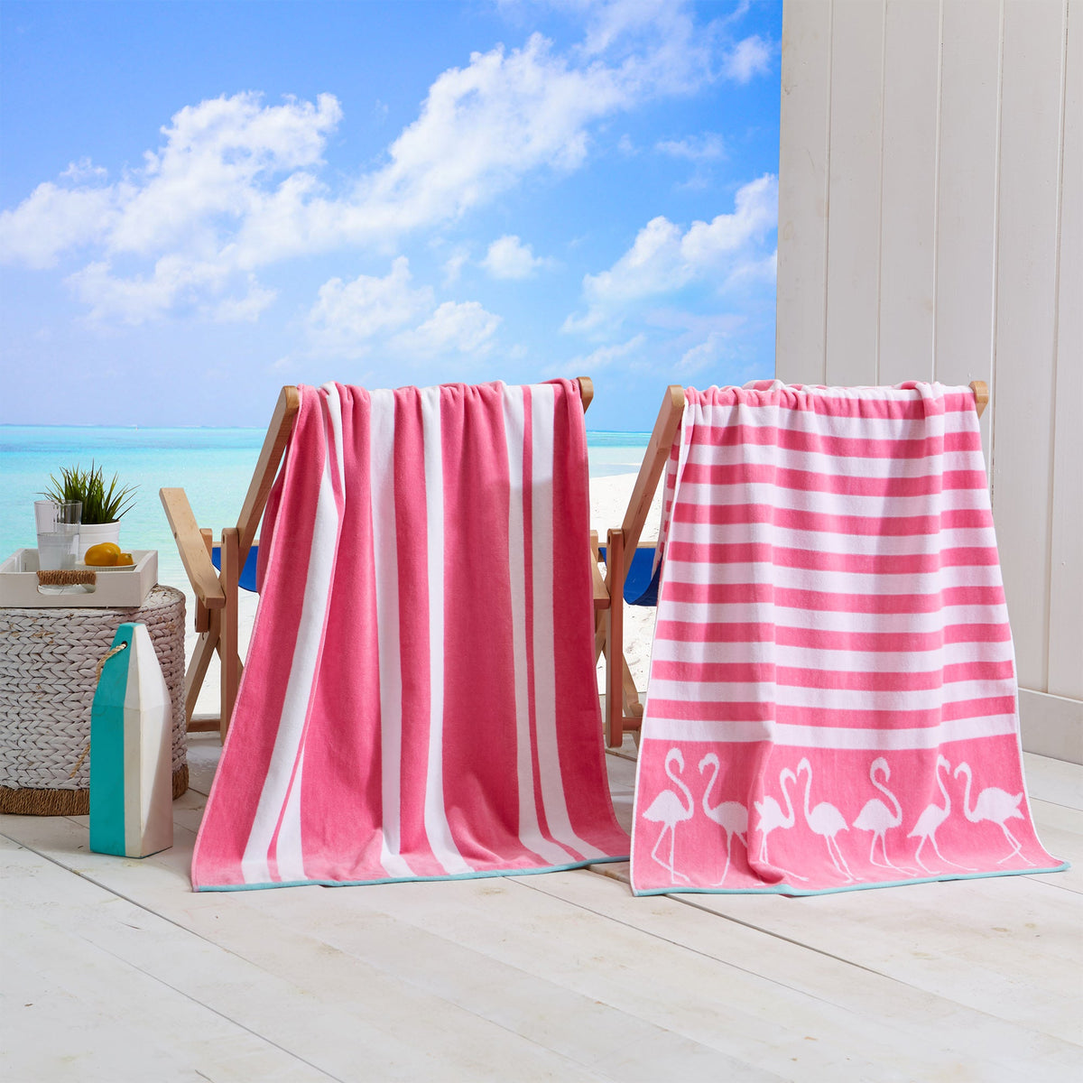 Two pink and white striped beach towels on a wooden deck with a beach view.