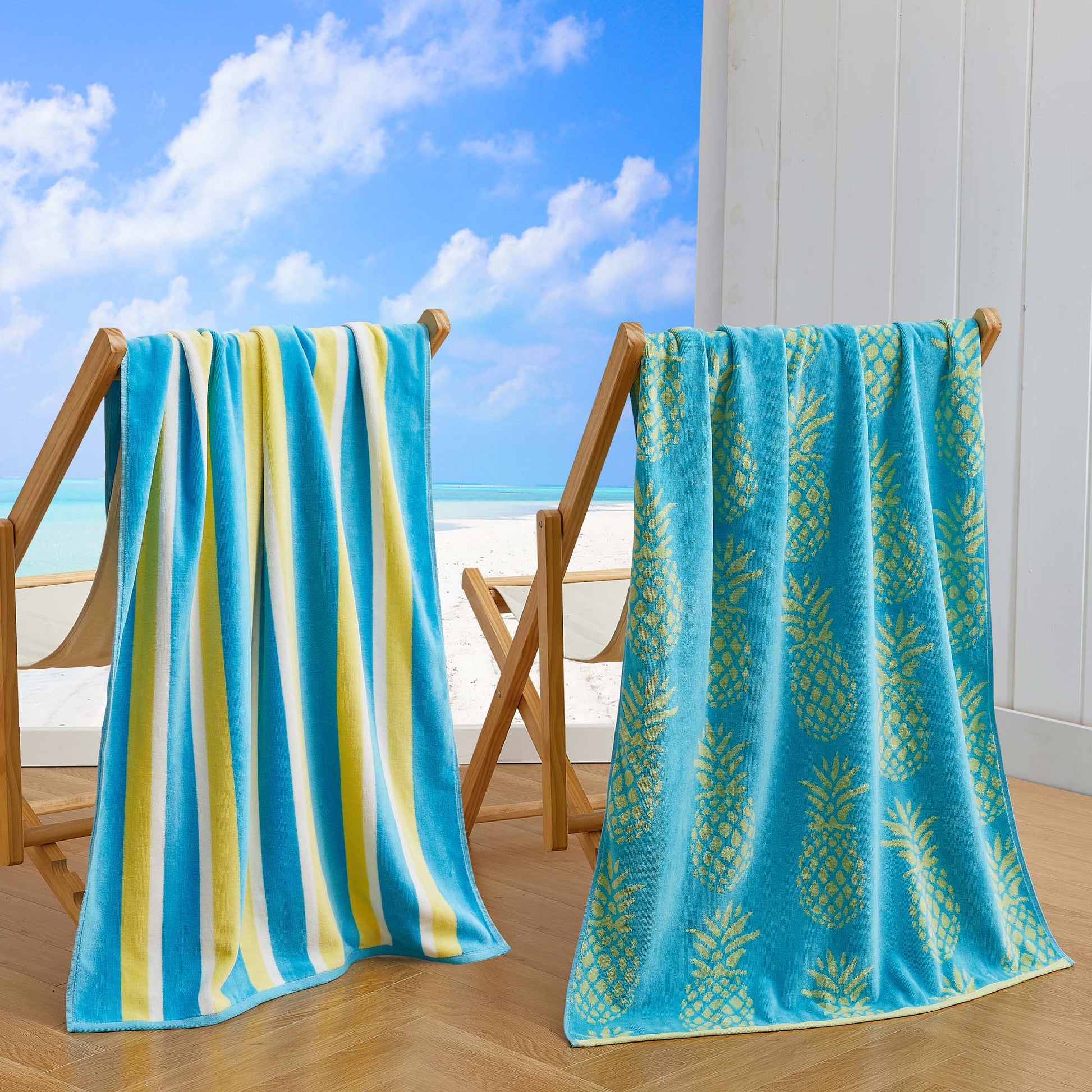 Two beach towels, one striped and one with pineapple pattern, on a wooden stand with a beach view in the background.