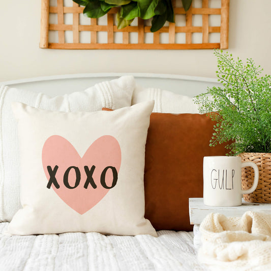 XOXO Valentine's Day Throw Farmhouse Pillow Cover 18x18 on a couch with a mug and plants for seasonal décor.
