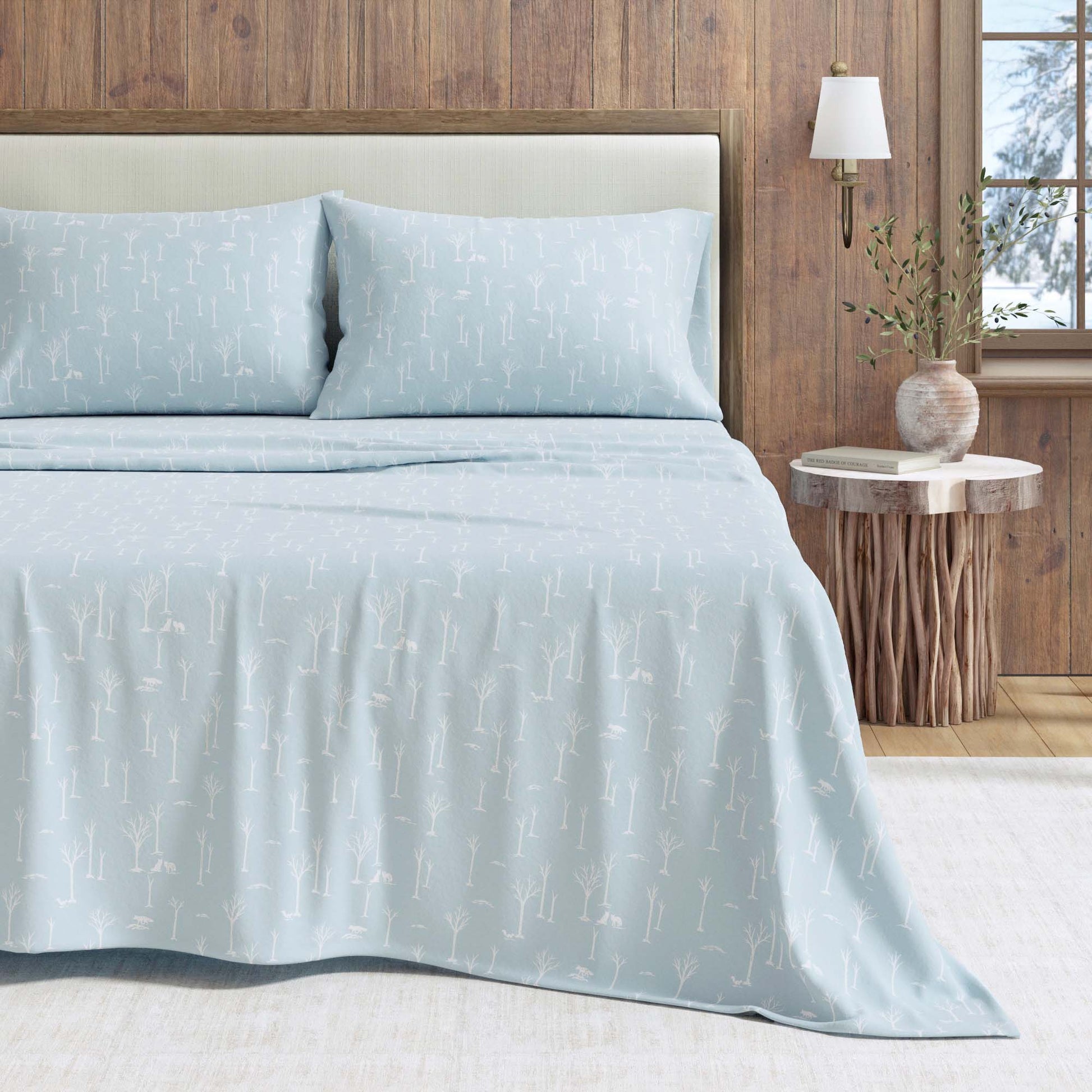 Light blue bedding set on a bed with a wooden headboard and side table.