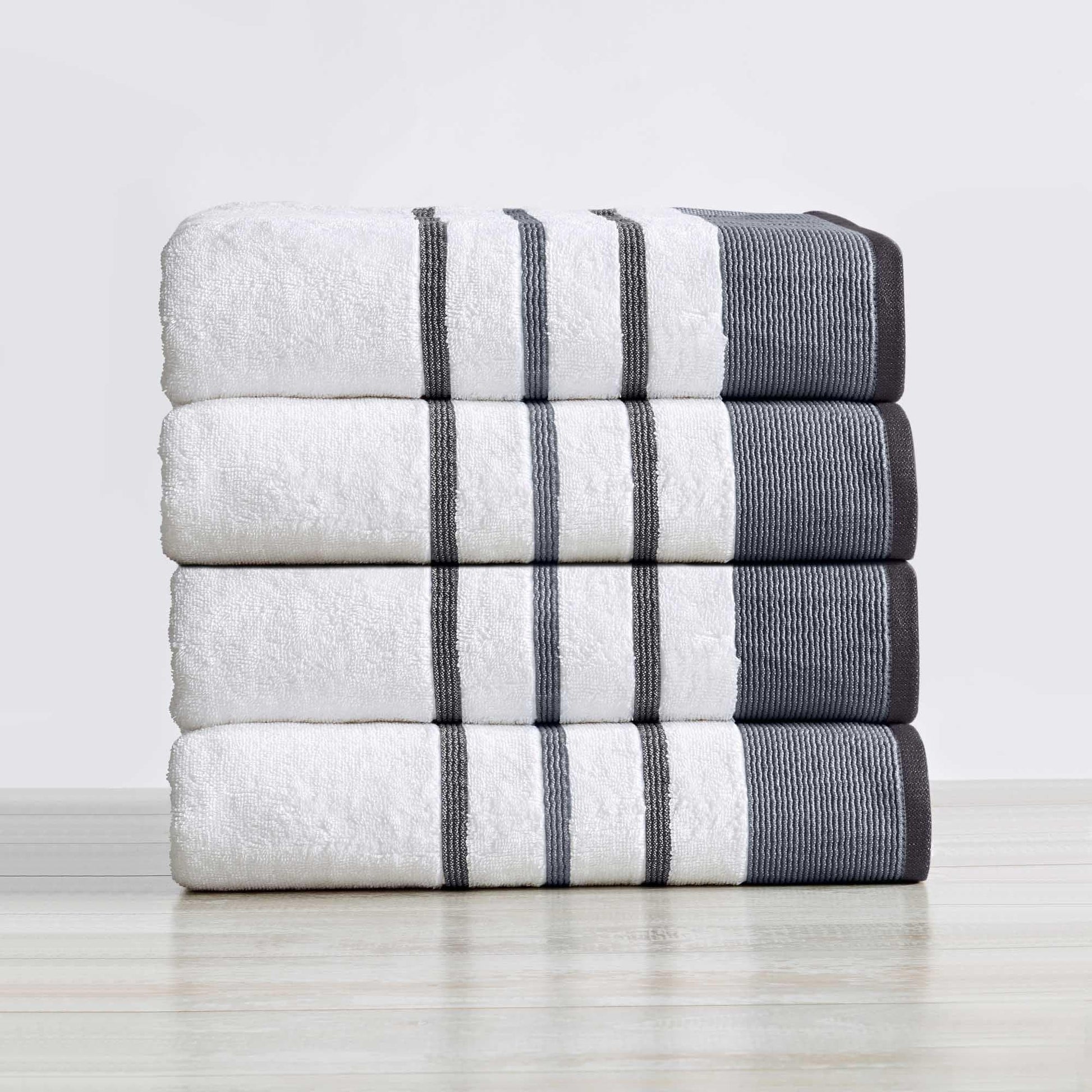 Stack of white towels with gray stripes on a light wooden surface.